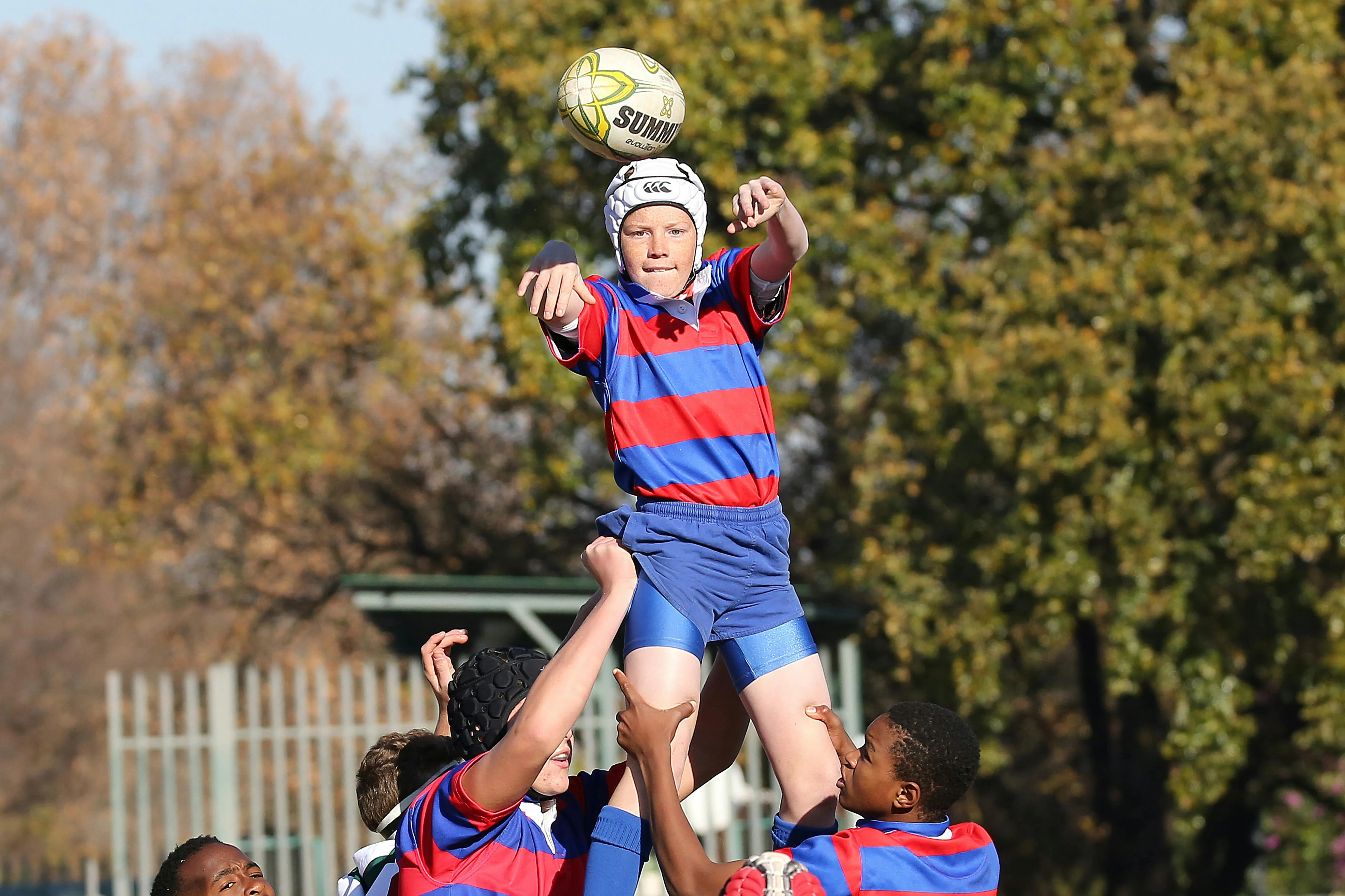 A young player catches the ball at a lineout during a junior rugby match