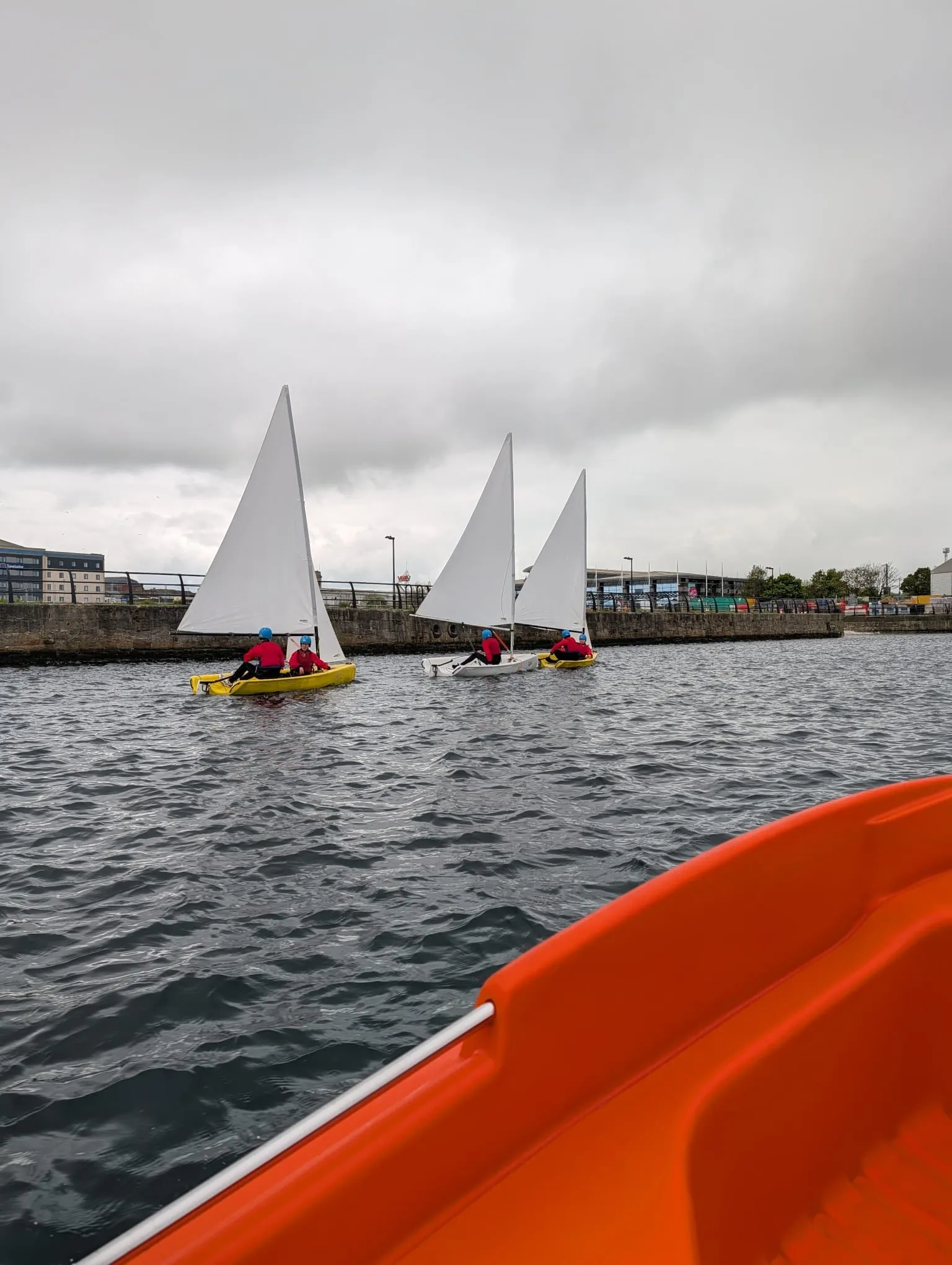 Sailing dinghies out on the water under a grey sky