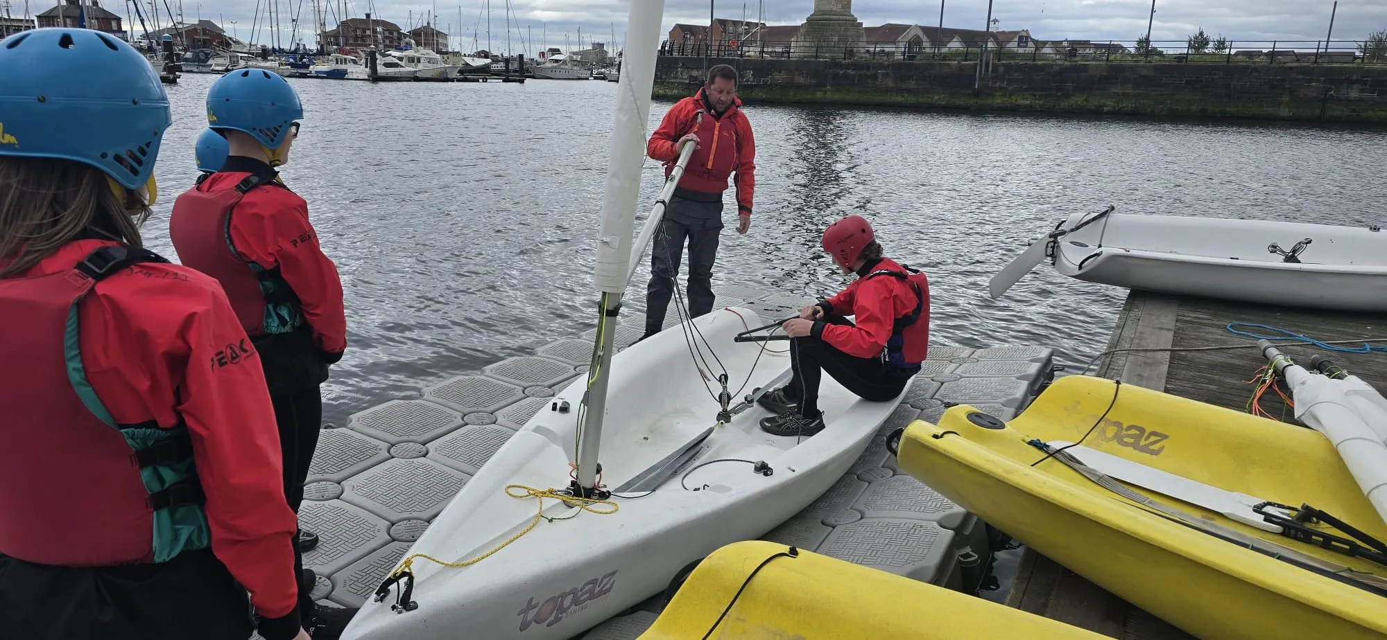 Young sailors preparing dinghies at the pontoon before a session