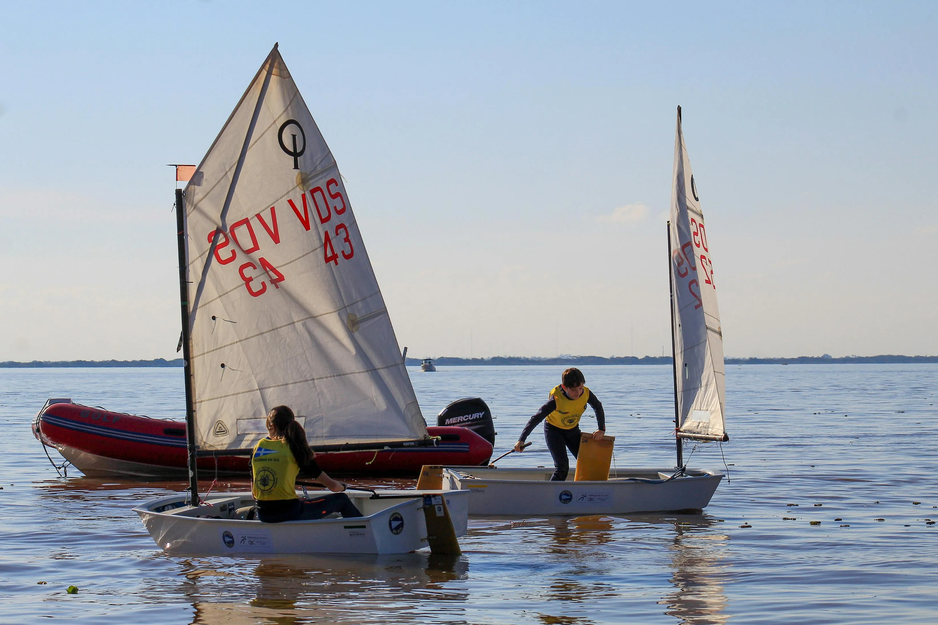 Two dinghies sailing side by side in the evening light